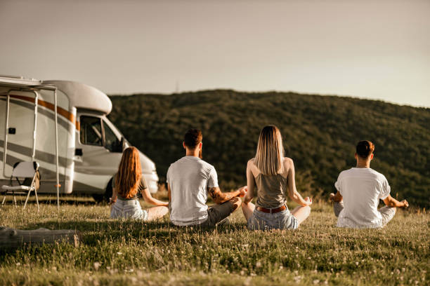 back view of friends meditating on camping in a trailer park. - lotus automobiles imagens e fotografias de stock