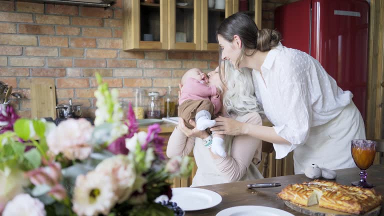 aged lady plays with granddaughter sitting in daughter hugs