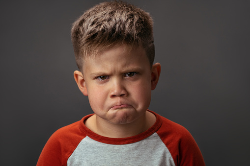 Preschool boy expresses sad emotions. Conflict concept. Close up portrait.
