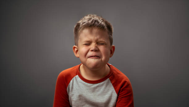 어린 아이는 얼굴을 찡그리며 눈을 감고 있다. 유치원 소년은 양치질을 꺼리는 의사를 표현합니다. 감정 개념 - unwillingness 뉴스 사진 이미지
