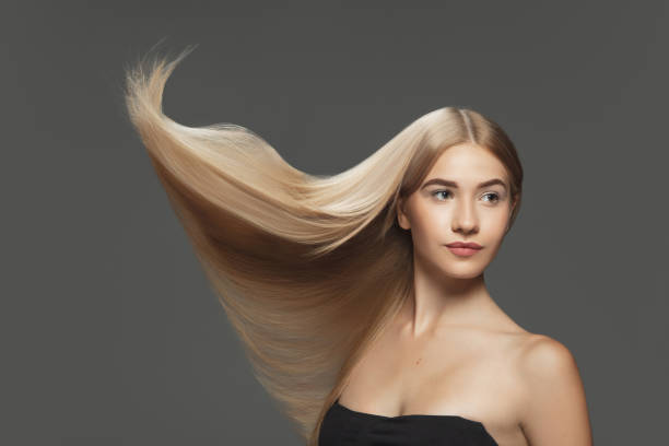 istock Beautiful model with long smooth, flying blonde hair isolated on dark studio background. 1281780027