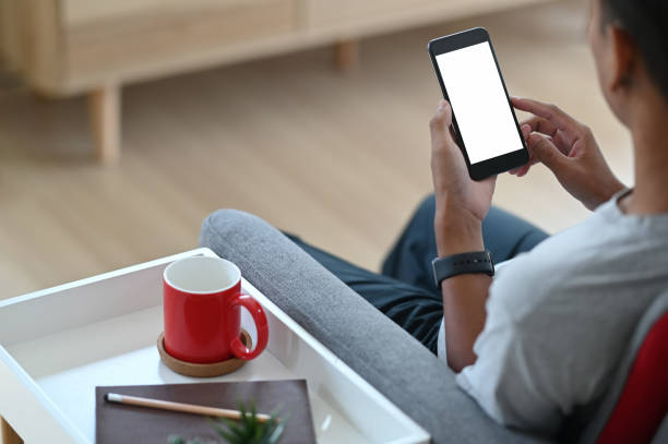 istock Cropped shot of men hand holding using mobile relax on sofa at home. Empty space for advertise text. 1281780185