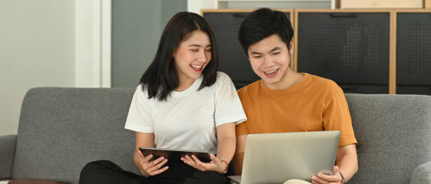 istock Loving couple spending time together with electronic device together on couch at home. 1281780199