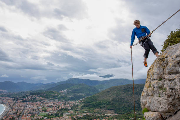 istock Climber rappels down a cliff above the hills and sea 1281781683
