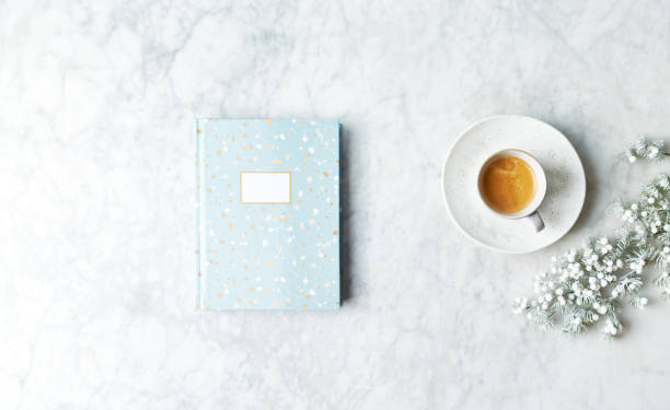 Cup of coffee, notebook and Christmas decorations on bright stone background. Copy space