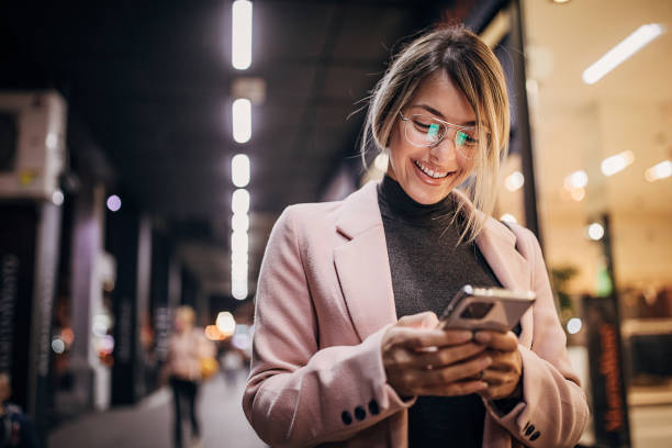 One young woman standing next to store window and using smart phone