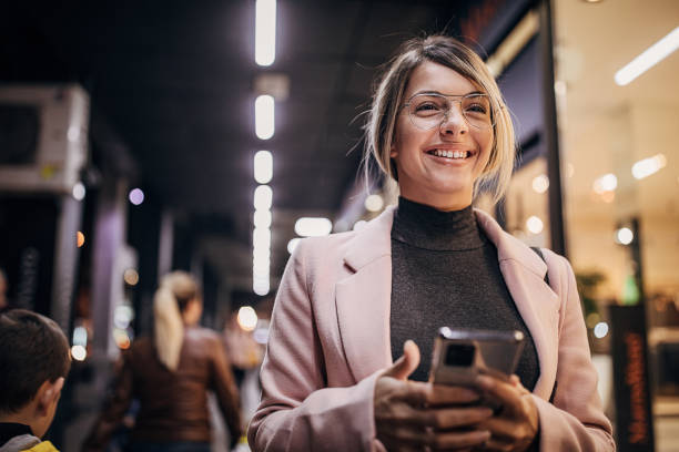 istock Young woman standing next to store window and using smart phone 1281784115