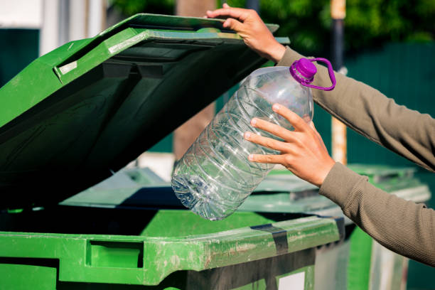 istock Man throwing out big plastic aqua bottle in to green garbage container. Used empty large plastic bottle. 1281785031