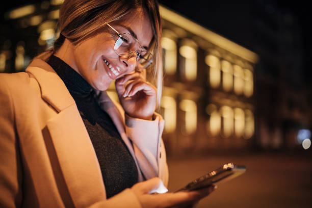 istock Happy woman using smart phone outdoors in the city at night 1281785052