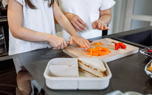 お弁当箱のために野菜を切るように娘に教える認識できない母親 - child human hand sandwich lunch box ストックフォトと画像