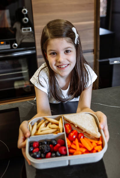 fille heureuse affichant la boîte à lunch remplie de nourriture saine - child human hand sandwich lunch box photos et images de collection