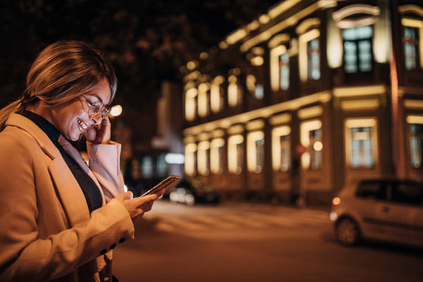 Young woman using smart phone outdoors in the city at night
