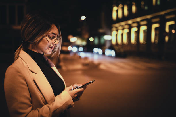 istock Woman using smart phone outdoors in the city at night 1281785279