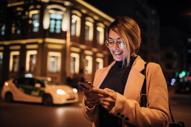 istock Cheerful woman using smart phone outdoors in the city at night 1281785406
