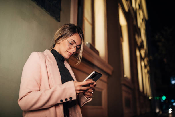 istock Woman using mobile phone outdoors in the city at night 1281786236