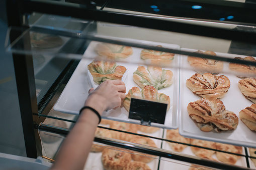 Asian chinese beautiful woman buying pastries from a cafe selecting holding a tray
