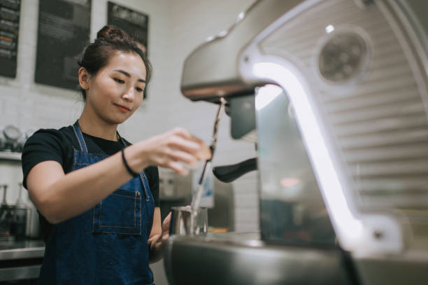 eine asiatische chinesische barista, die kaffee mit kaffeemaschine im café macht - duftend fotos stock-fotos und bilder