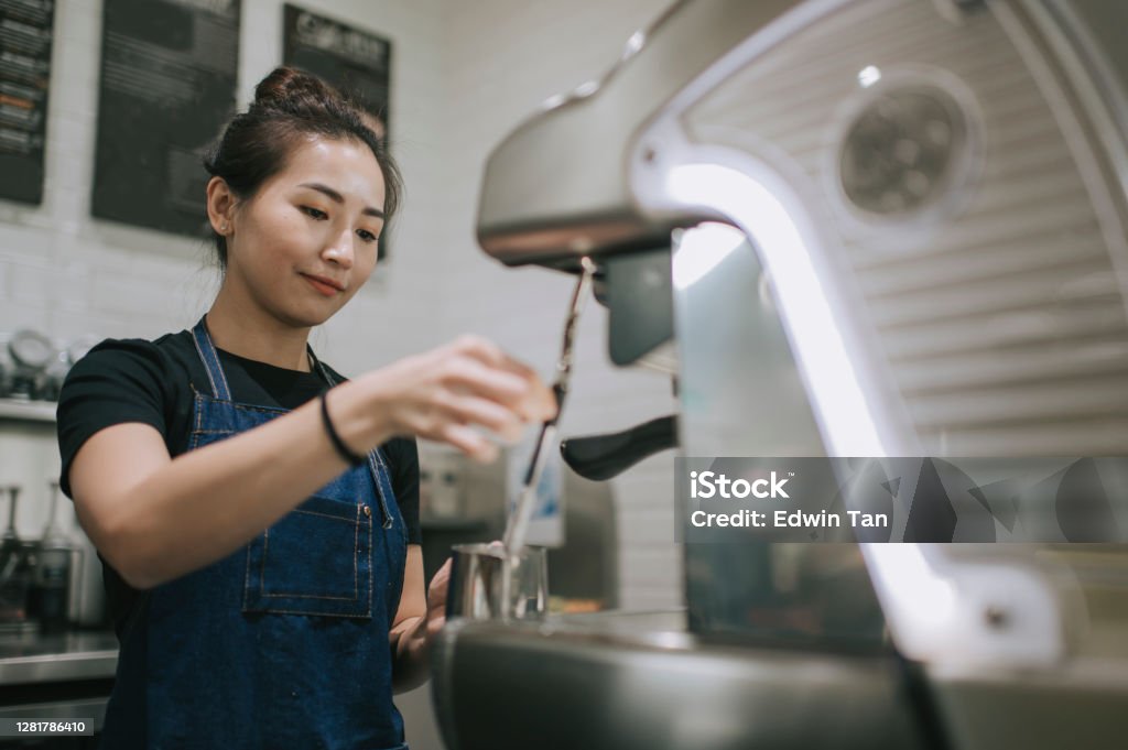 An asian chinese female barista making coffee with coffee machine at the cafe Occupation Stock Photo