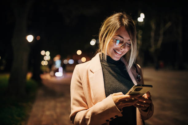 istock Beautiful woman using phone in park at night 1281786418