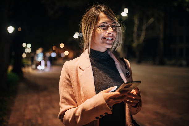 istock Beautiful woman using phone in park at night 1281786983