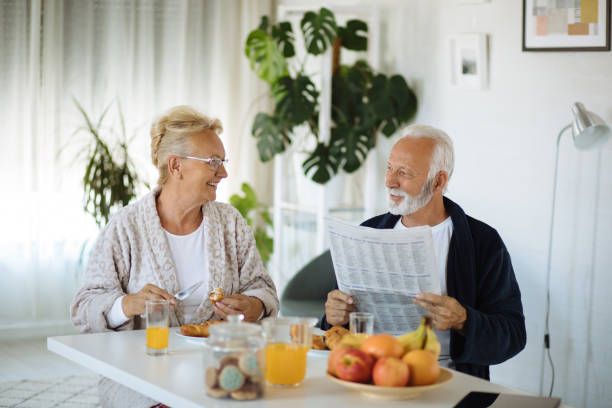 istock Senior couple in dining room eating breakfast and reading newspaper 1281789843