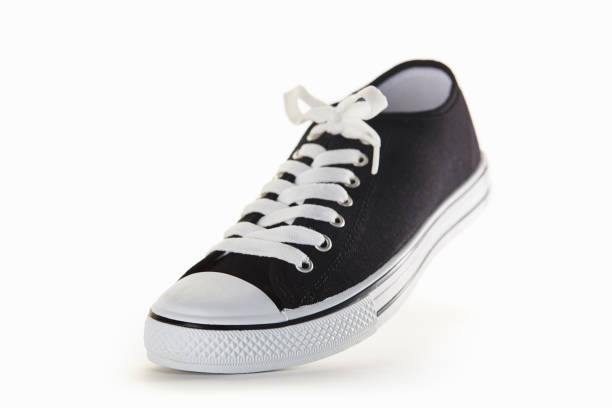 Closeup of a pair of new white men's shoes on a wood floor with shadows. 
