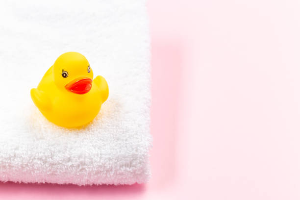 istock One rubber duck on white terry bath towel, pink background with place for copy space, horizontal 1281791105
