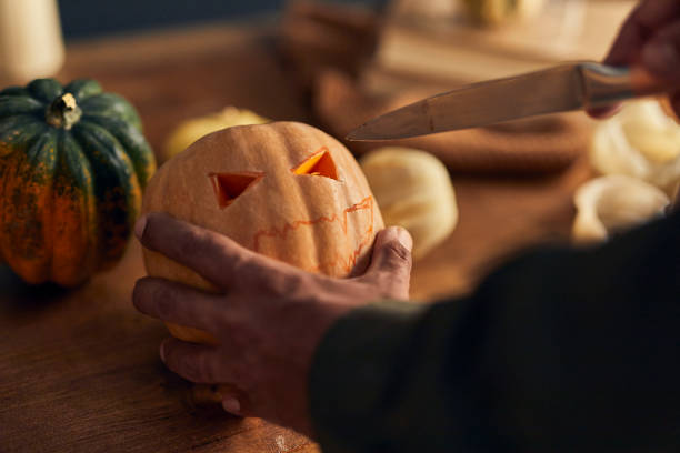 istock Man sticking a knife into a Halloween pumpkin horizontal 1281791489
