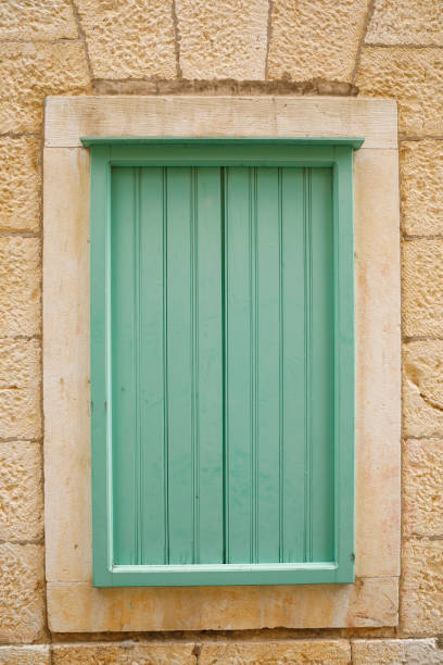 istock Vintage green window with shutters on stone wall. 1281792997