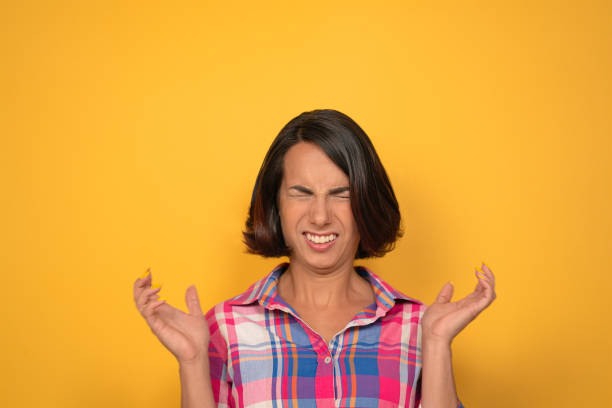 Caucasian woman grimacing screwed up her eyes. Young brunette tasted sour food. Isolated on yellow background. Copy space Caucasian woman grimacing screwed up her eyes. Young brunette tasted sour food. Isolated on yellow background. Copy space. sour face stock pictures, royalty-free photos & images
