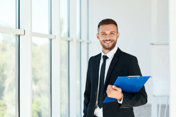 istock Handsome smiling businessman with clipboard in a bright modern office 1281795370