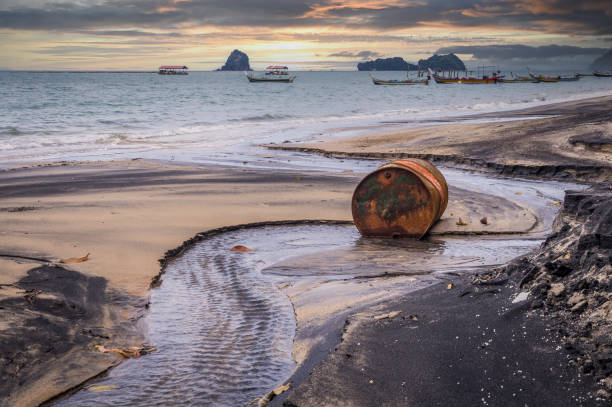 Old rusty barrel oil on beach in Asia on sunset stock photo