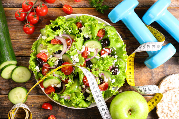 istock diet food concept- vegetable salad with dumbbell and meter 1281798462