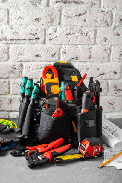 istock Electrician's tools in a black construction bag on a gray table against a white brick wall. Construction tools of an installer or electrician. Space for text 1281799875