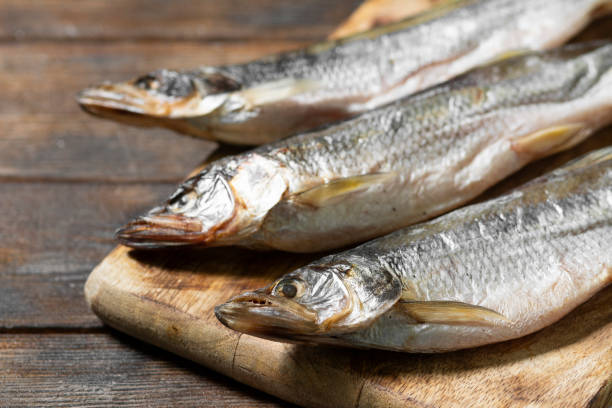 istock Smoked or dried smelt fish on a wooden Board on a gray kitchen table. Space for text 1281799895