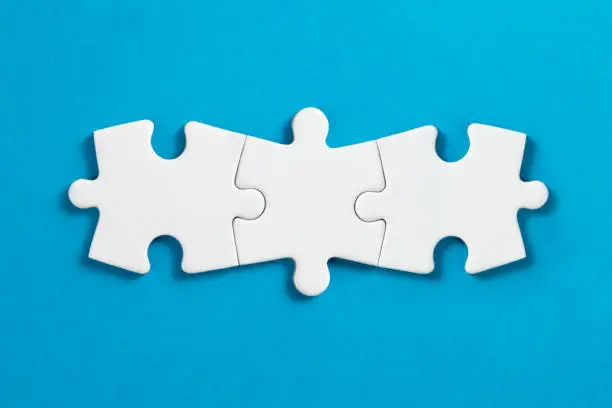 White puzzle pieces comes together on blue background.