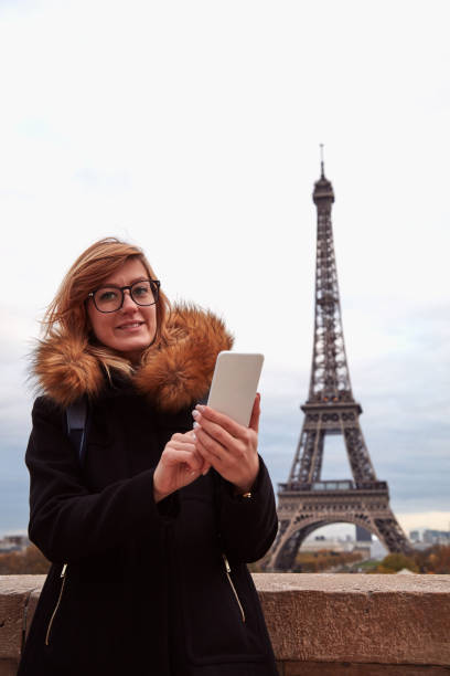 istock Girl using cellphone with Paris city background and Eiffel tower. 1281801265