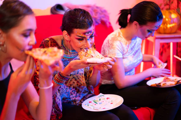 girls with halloween costumes eating pizza at a halloween party. - medium group of people imagens e fotografias de stock