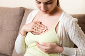 pregnant girl checks her breasts. prevention of breast cancer