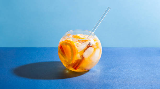 Sangria punch cocktail with orange, apple and cinnamon on blue background.