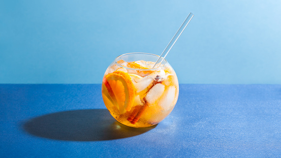 Sangria punch cocktail with orange, apple and cinnamon on blue background. Fruit drink for party
