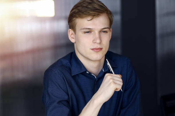 istock Young blond businessman thinking about strategy at his working place with computer in a darkened office, glare of light on the background 1281807420