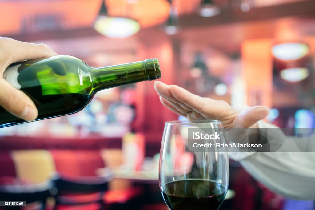 Woman hand rejecting more alcohol from wine bottle in bar Womans hand rejecting more alcohol from wine bottle in bar concept for alcoholism or drunk driving Alcohol - Drink Stock Photo