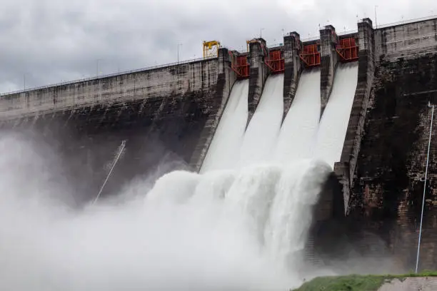 Photo of Water flowing over floodgates of a dam at Khun Dan Prakan Chon.