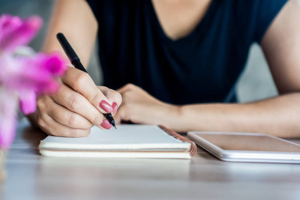 istock woman hand holding a pen and using smart phone for studying  online, e- learning from home concept 1281814143