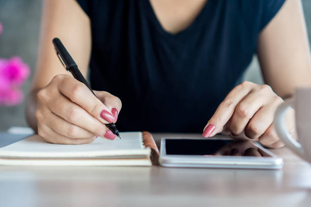 istock woman hand holding a pen and using smart phone for studying  online, e- learning from home concept 1281814168