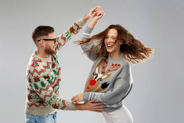 couple dancing at christmas ugly sweaters party celebration, fun and holidays concept - happy couple wearing ugly sweaters dancing at christmas party christmas ugliness sweater nerd stock pictures, royalty-free photos & images