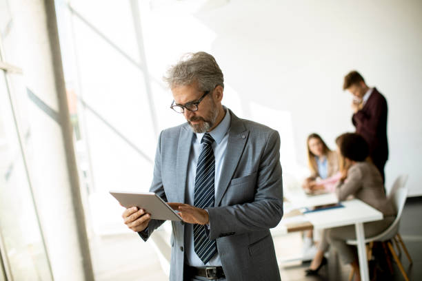 istock Handsome mature businessman using his tablet in the office 1281823621