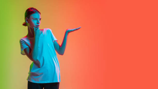 istock Young caucasian girl's portrait on gradient green-orange studio background in neon light 1281824062
