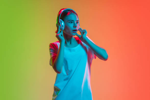 istock Young caucasian girl's portrait on gradient green-orange studio background in neon light 1281824743